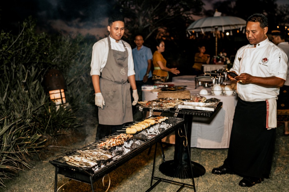 Chefs grilling satay skewers at an outdoor night event
