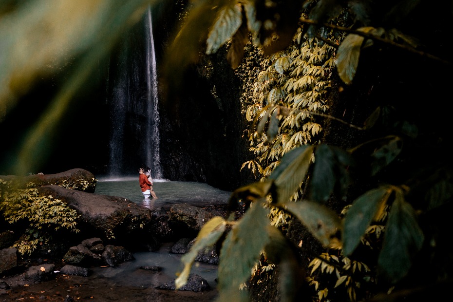 Couple enjoying a waterfall embrace in a beautiful tropical oasis