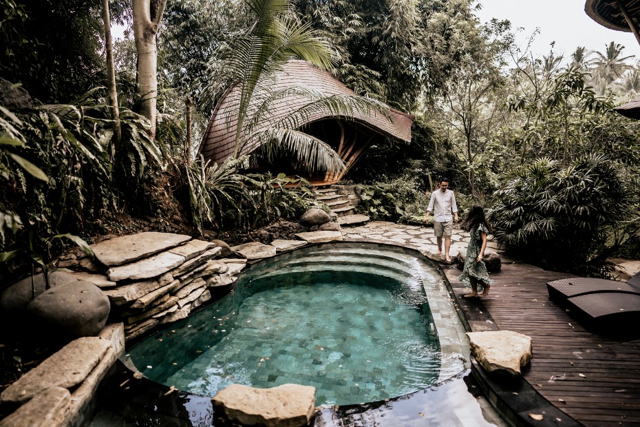 Couple walking near pool and a unique jungle style house