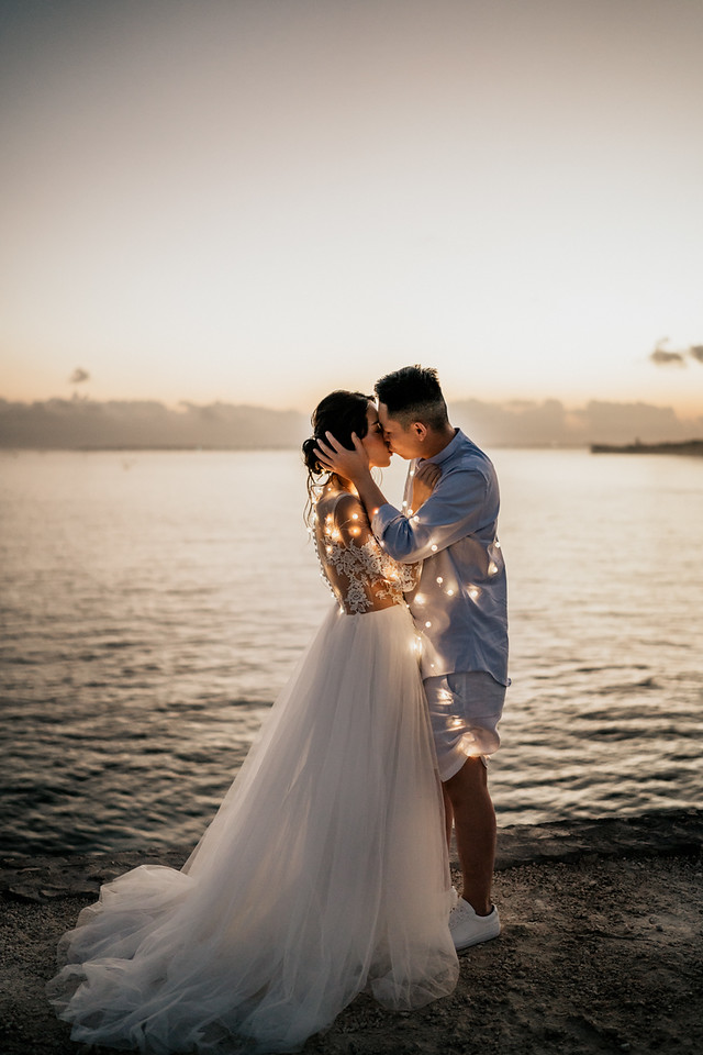 Couple kissing at sunset during a beach wedding ceremony