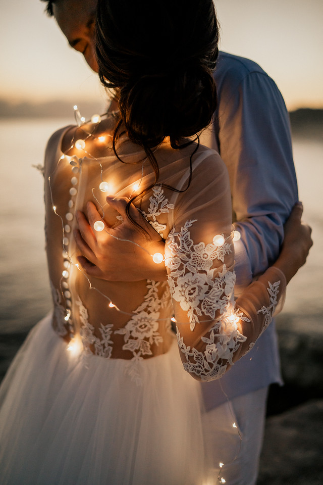 Romantic couple embracing, bride in dress with fairy lights, wedding