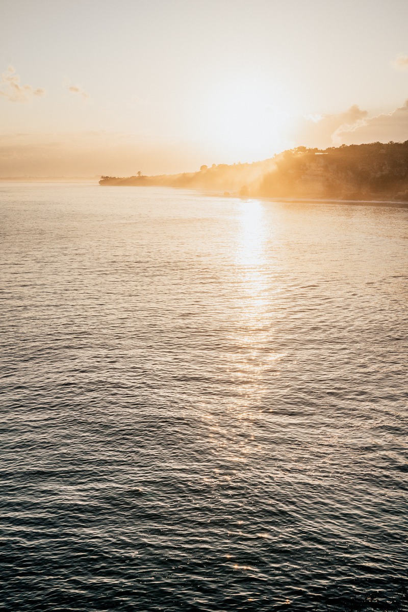 Golden sunset reflecting on the ocean with a hazy shoreline
