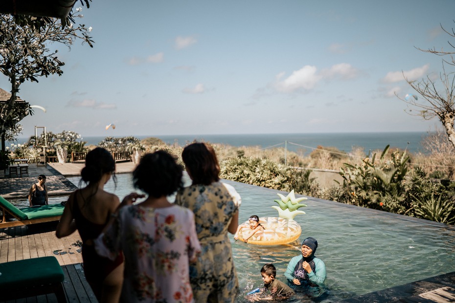 People enjoying a sunny day by a pool with ocean views