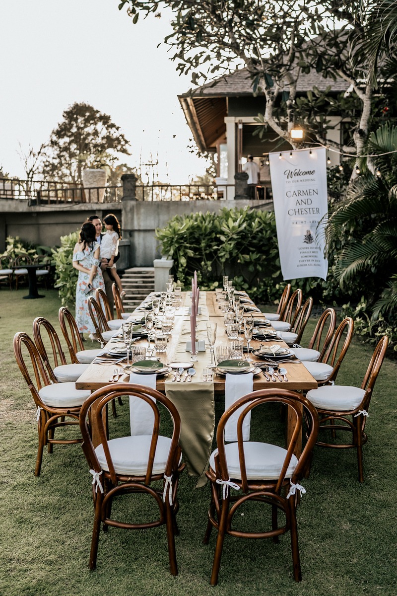 Wedding reception table set outdoors with family in the background