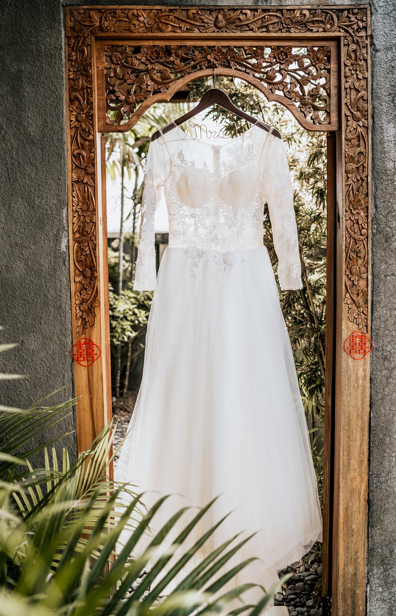 Elegant white wedding dress hanging in carved wooden doorway