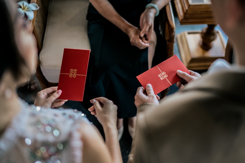 People holding red envelopes with a double happiness symbol