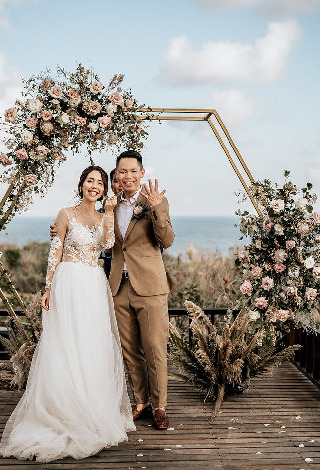 Happy couple shows rings at outdoor wedding ceremony