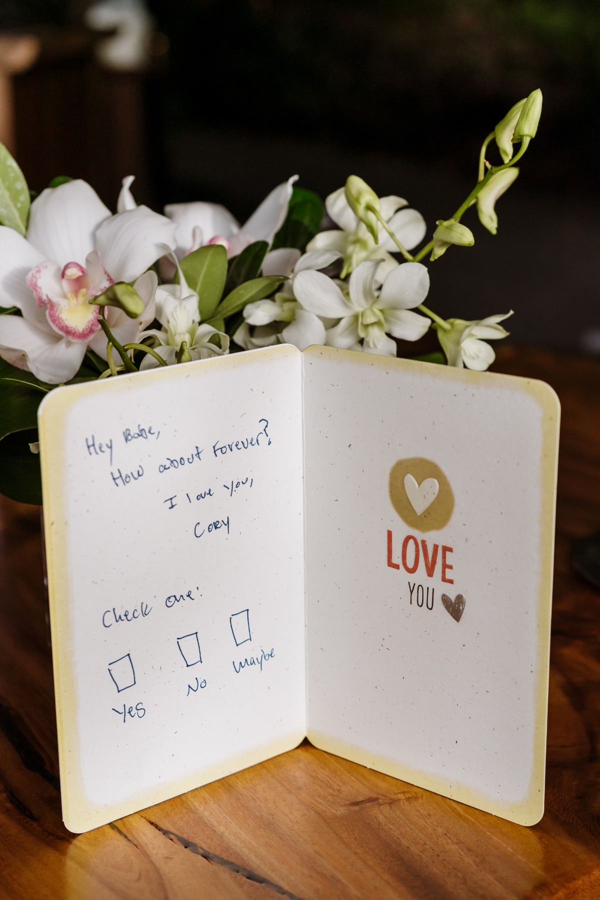 Love card with forever question near white flowers