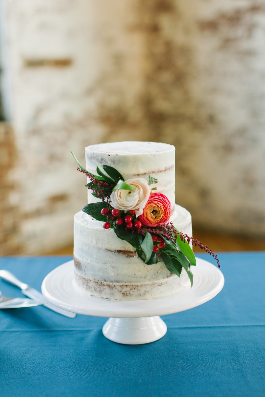 Two-tiered wedding cake decorated with flowers on a white cake stand