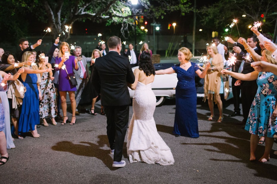 Newlyweds walk through a sparkler tunnel at their wedding celebration