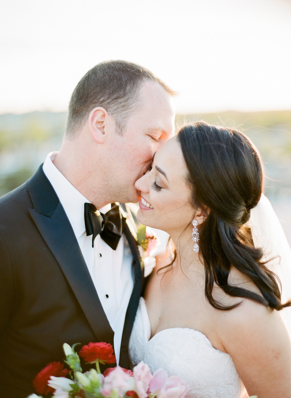 Groom kissing bride on the forehead, celebrating their wedding day