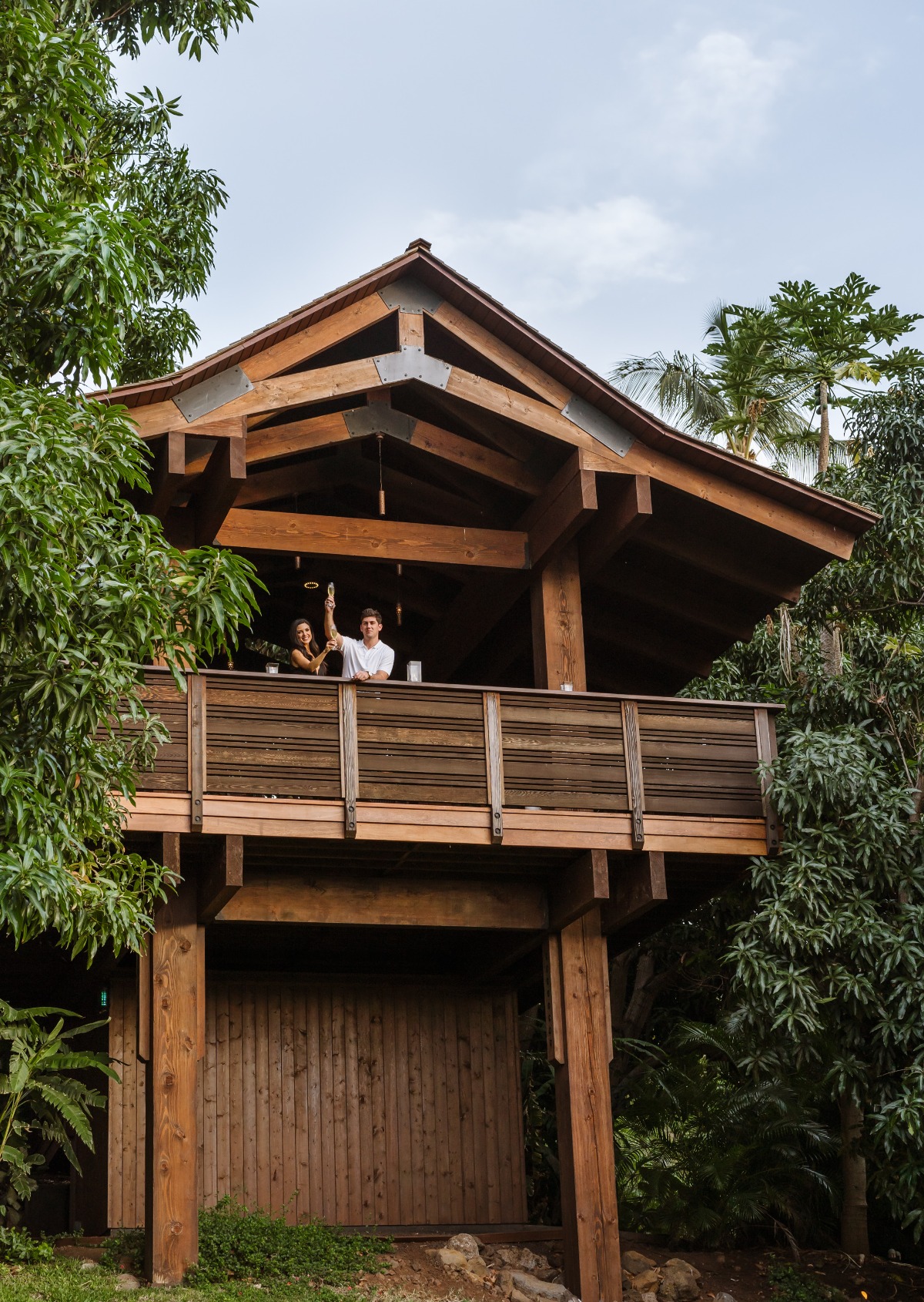 Couple on a wooden treehouse deck in tropical foliage