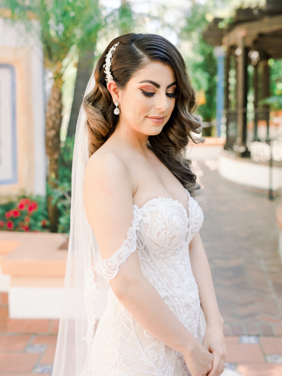 Elegant bride in lace wedding gown with veil outdoors