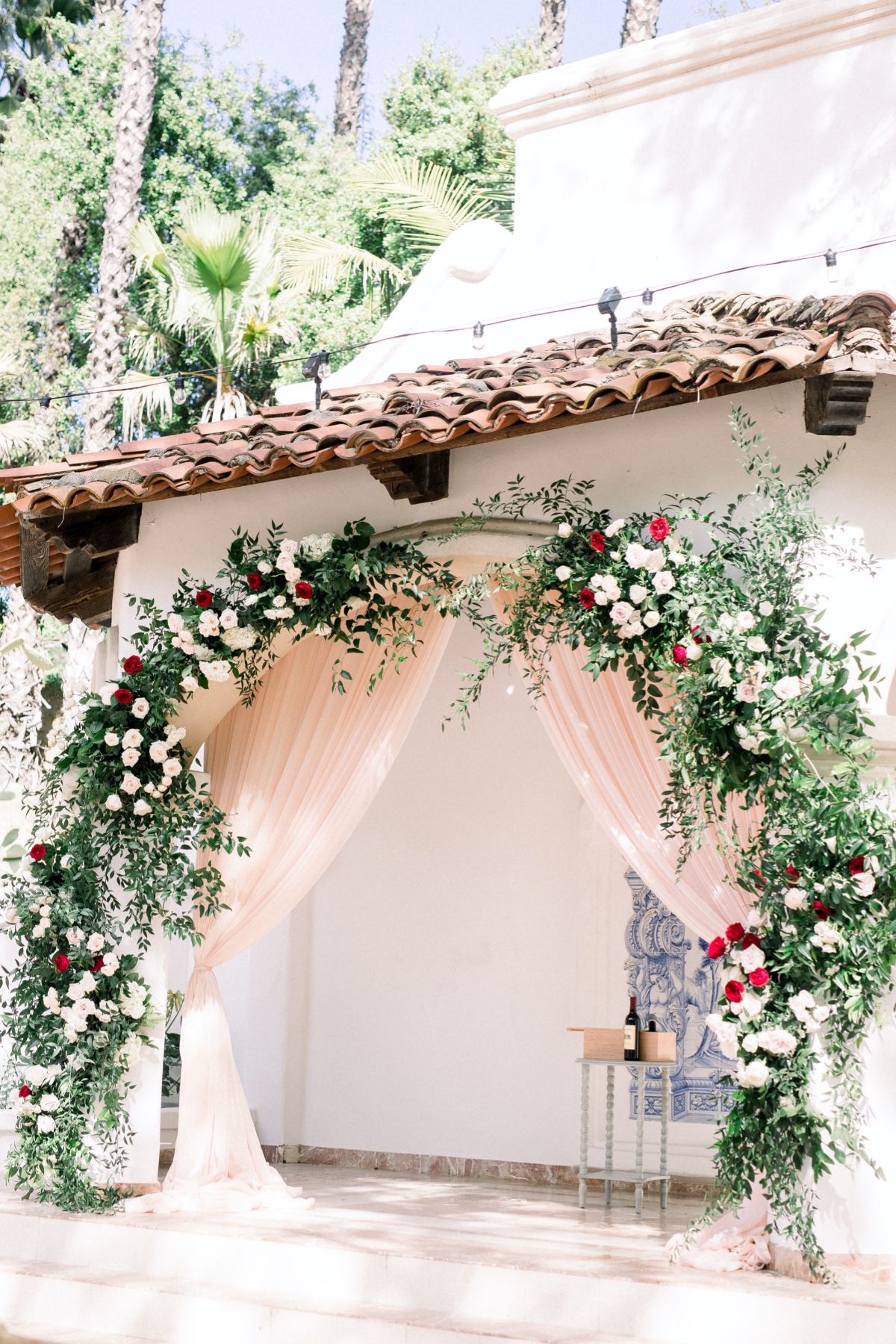 Garden roses and greenery floral arch with blush backdrop