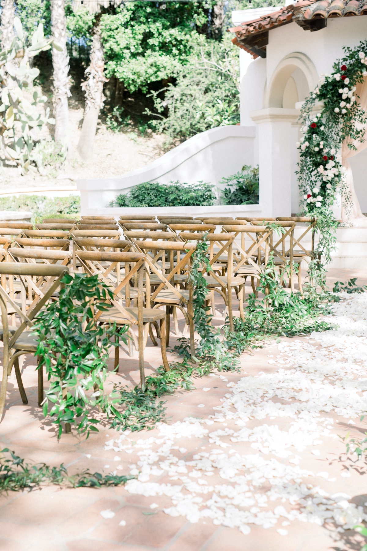 Petal strewn wedding aisle with decorated wood chairs