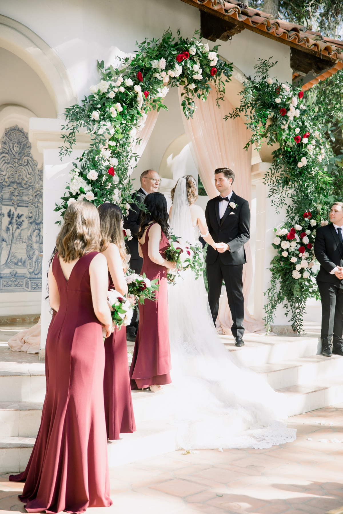 Bride and groom at altar with bridesmaids in maroon