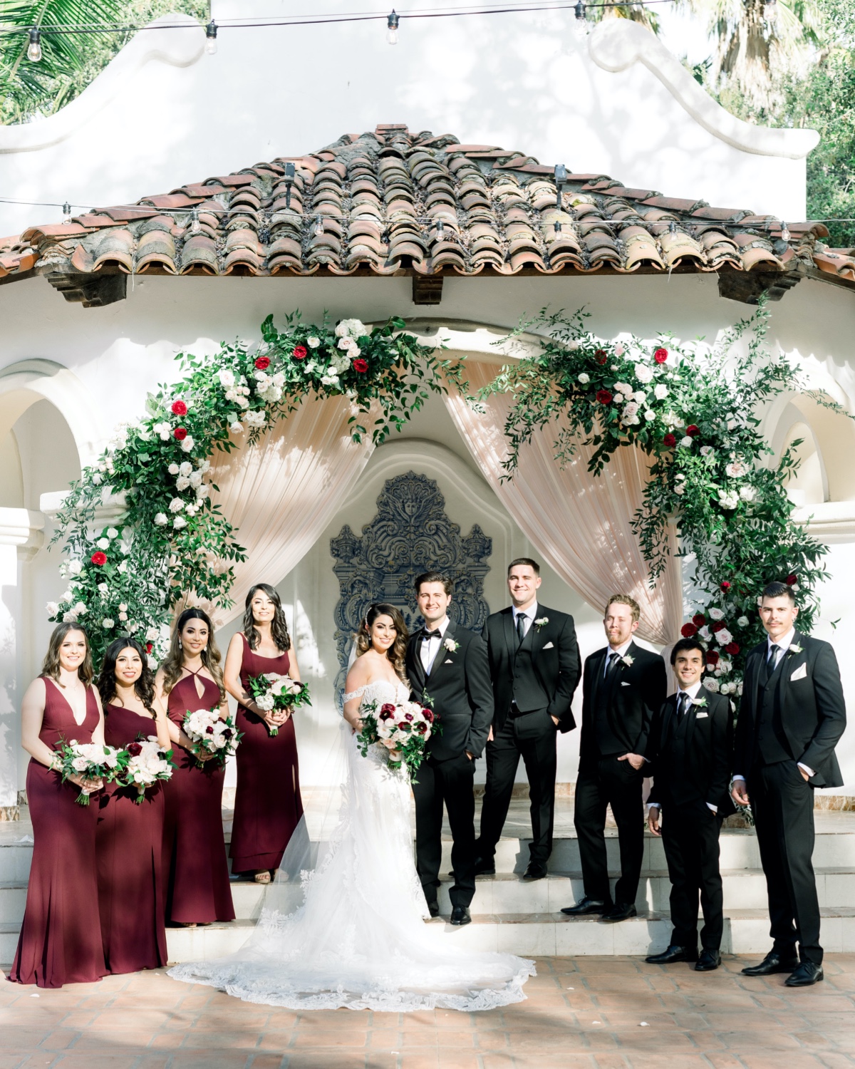 Bridal party in front of floral arch at wedding venue