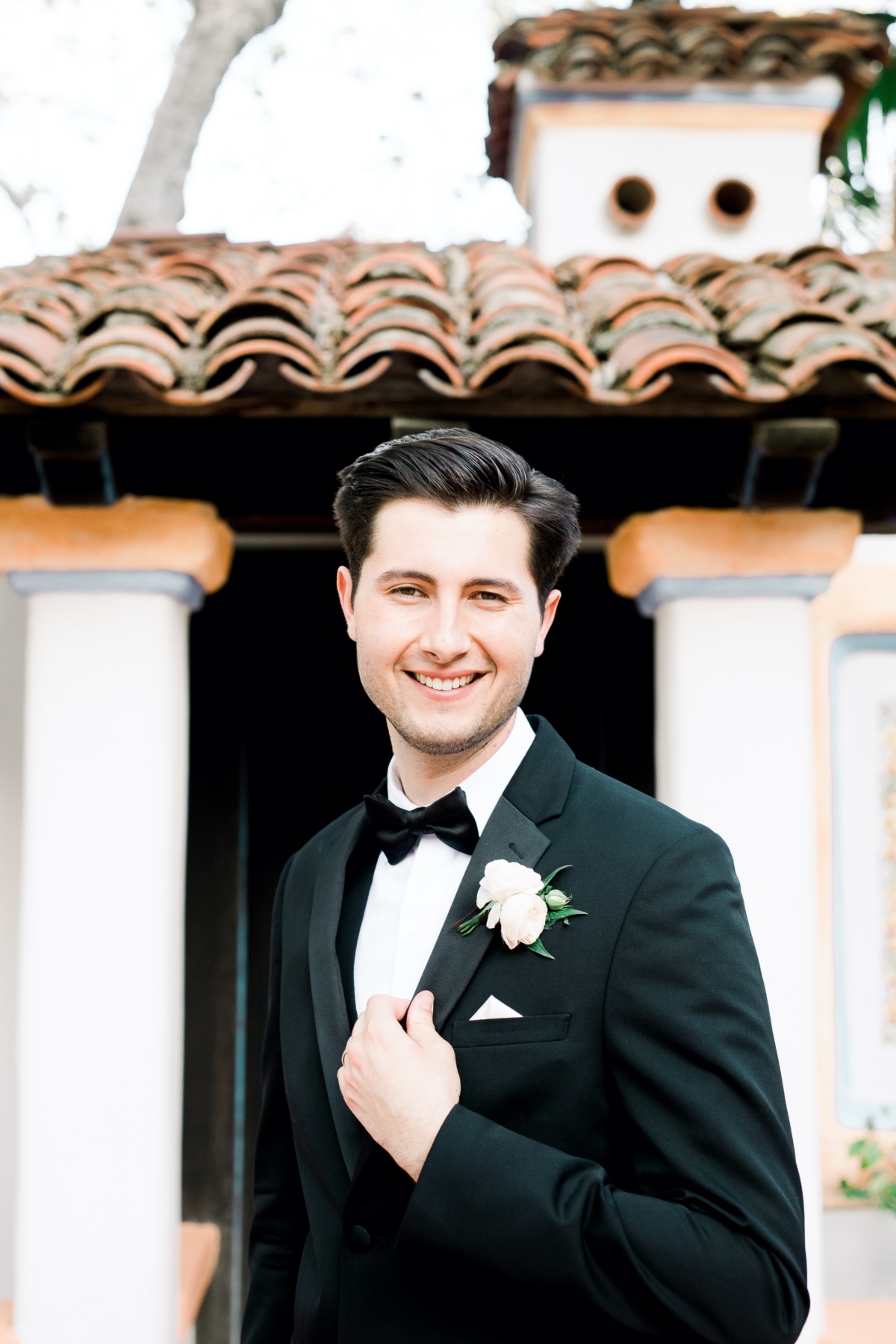Smiling groom in a tuxedo posing for a wedding photo
