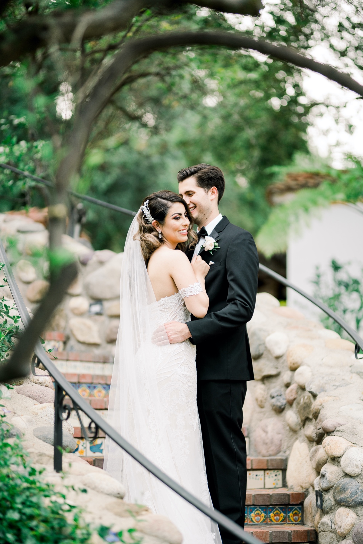Bride and groom embrace on stone staircase wedding day