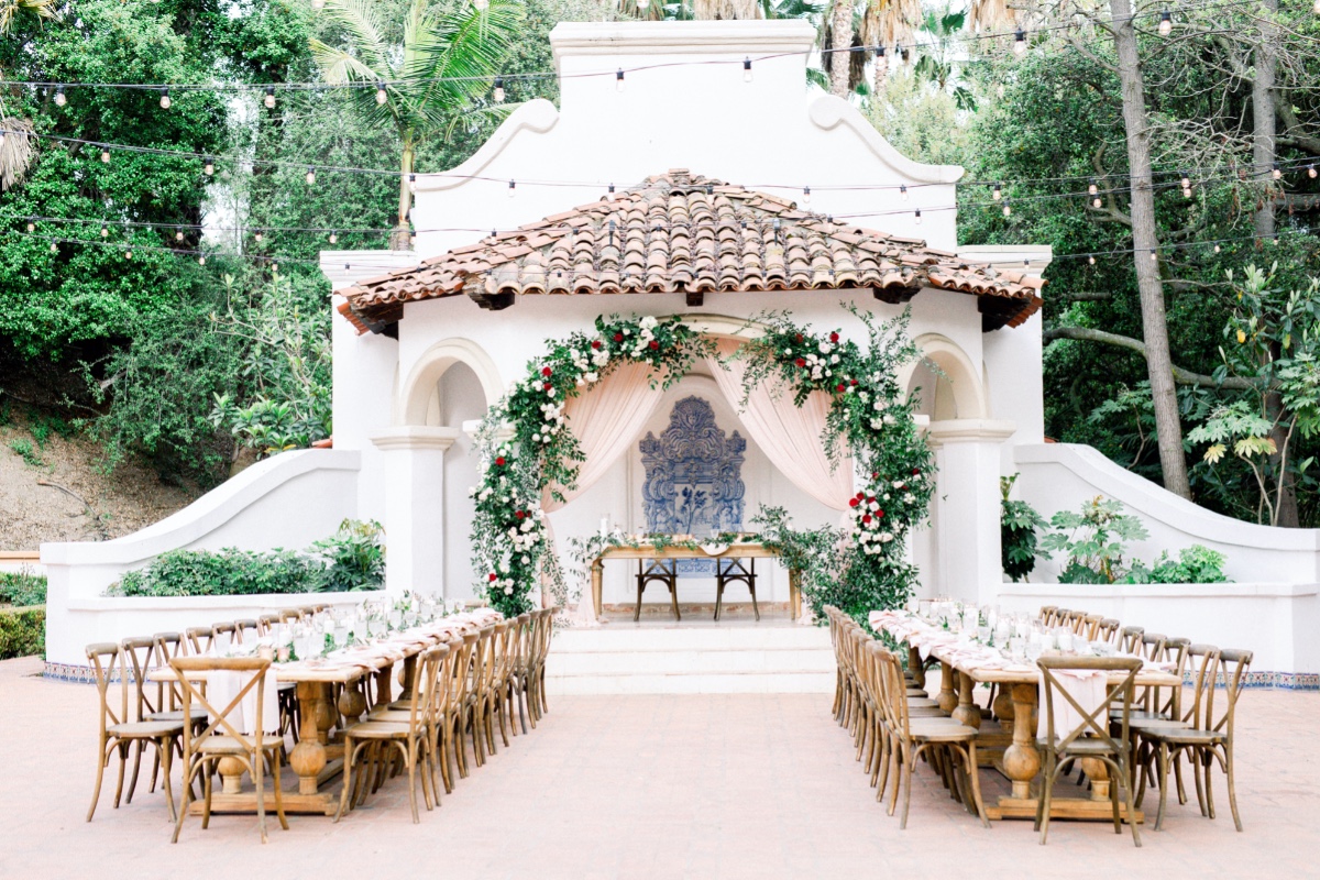 Outdoor wedding reception with floral archway and tables
