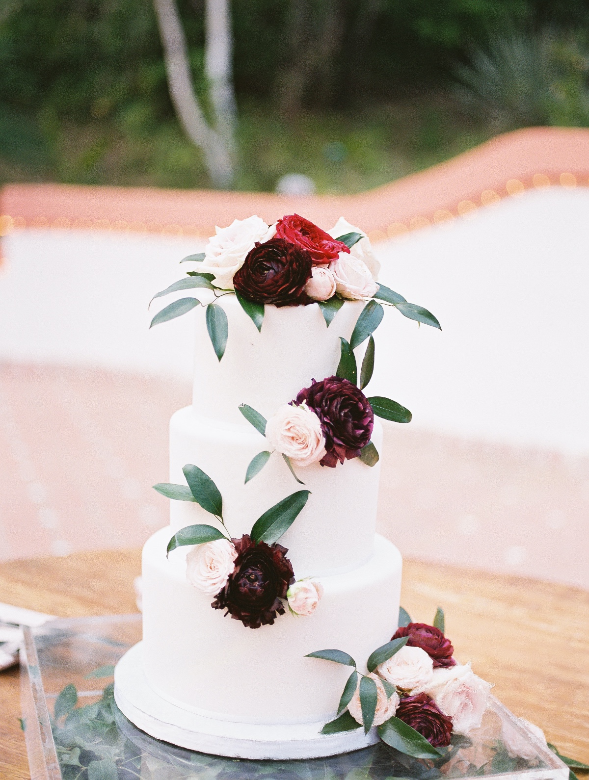 Elegant white wedding cake with burgundy and pink roses