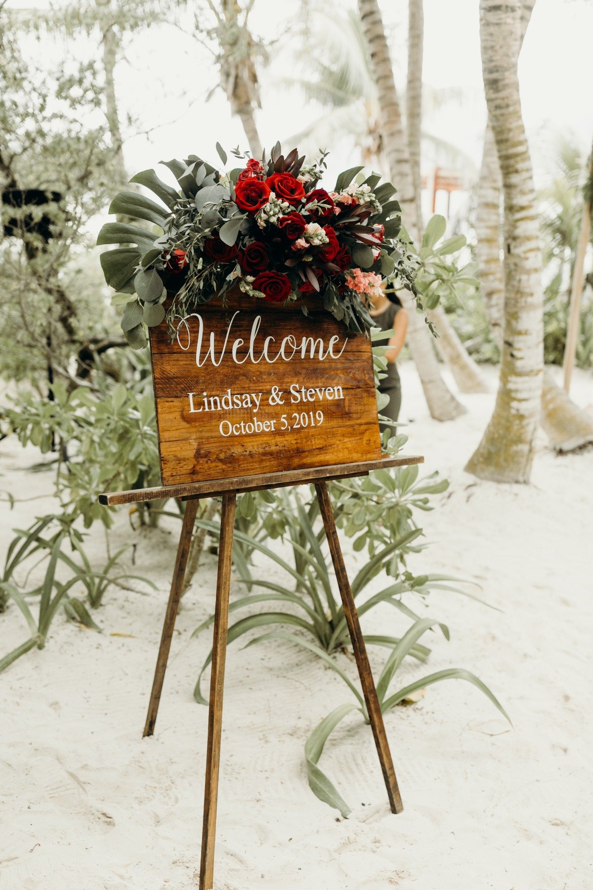 wooden welcome wedding sign with tropical floral arrangements