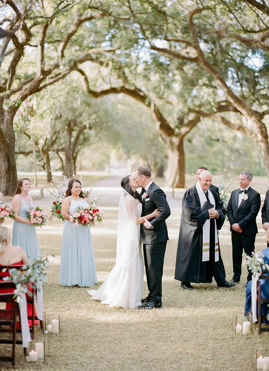 Bride and groom kiss during outdoor wedding ceremony