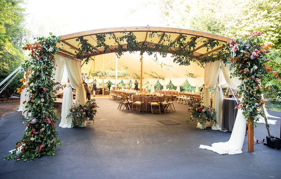 Tent entrance flower installation with lush vines