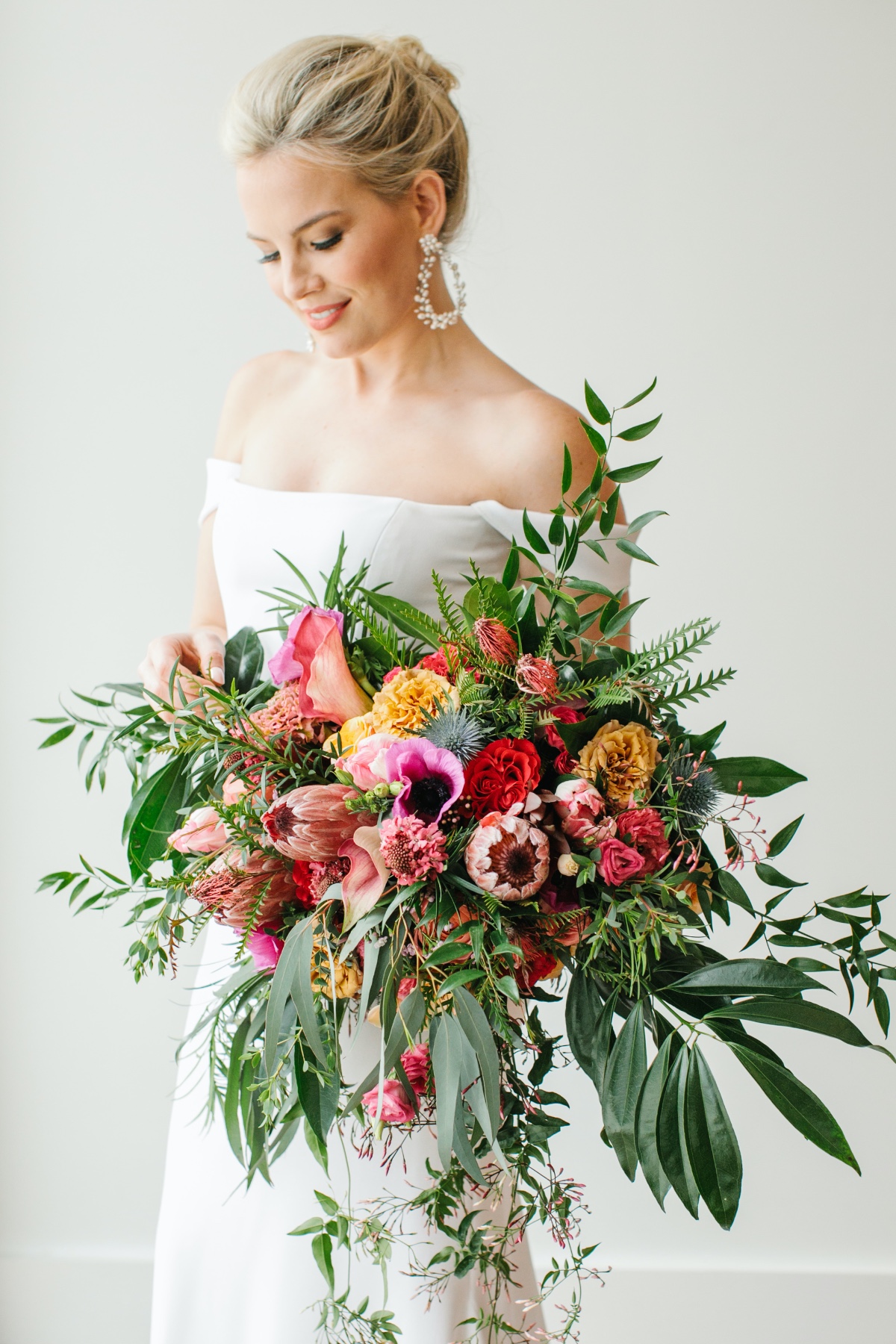lose wedding bouquet with protea, pink anemone, greenery and tropical florals