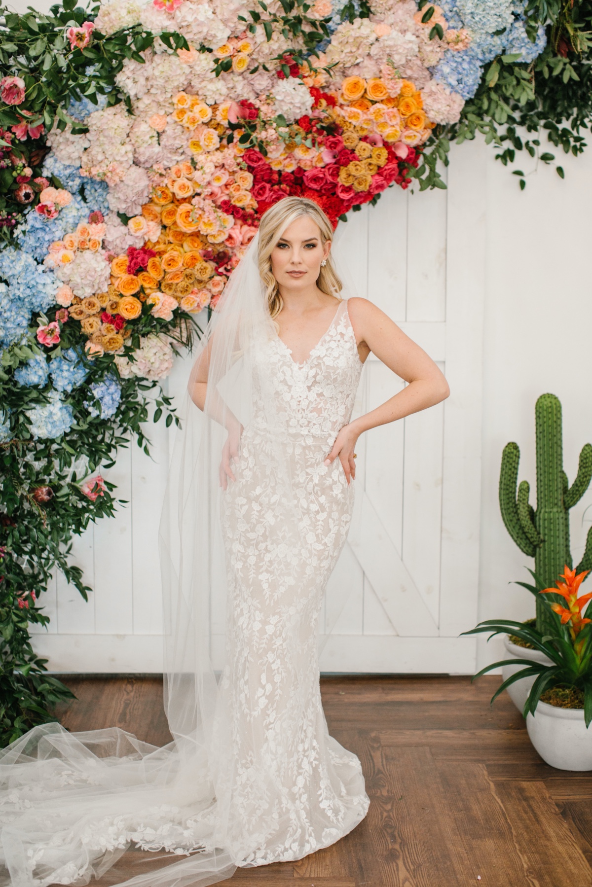 Lace wedding gown in front rainbow floral backdrop