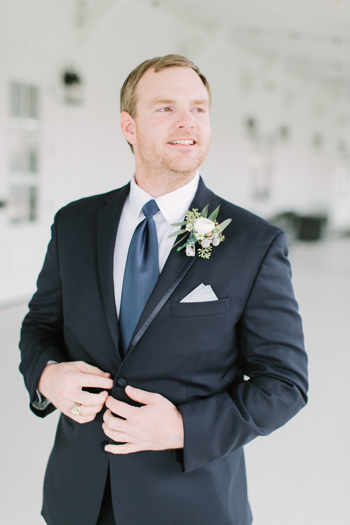 groom in black suit with blue tie and white boutonniÃ¨re