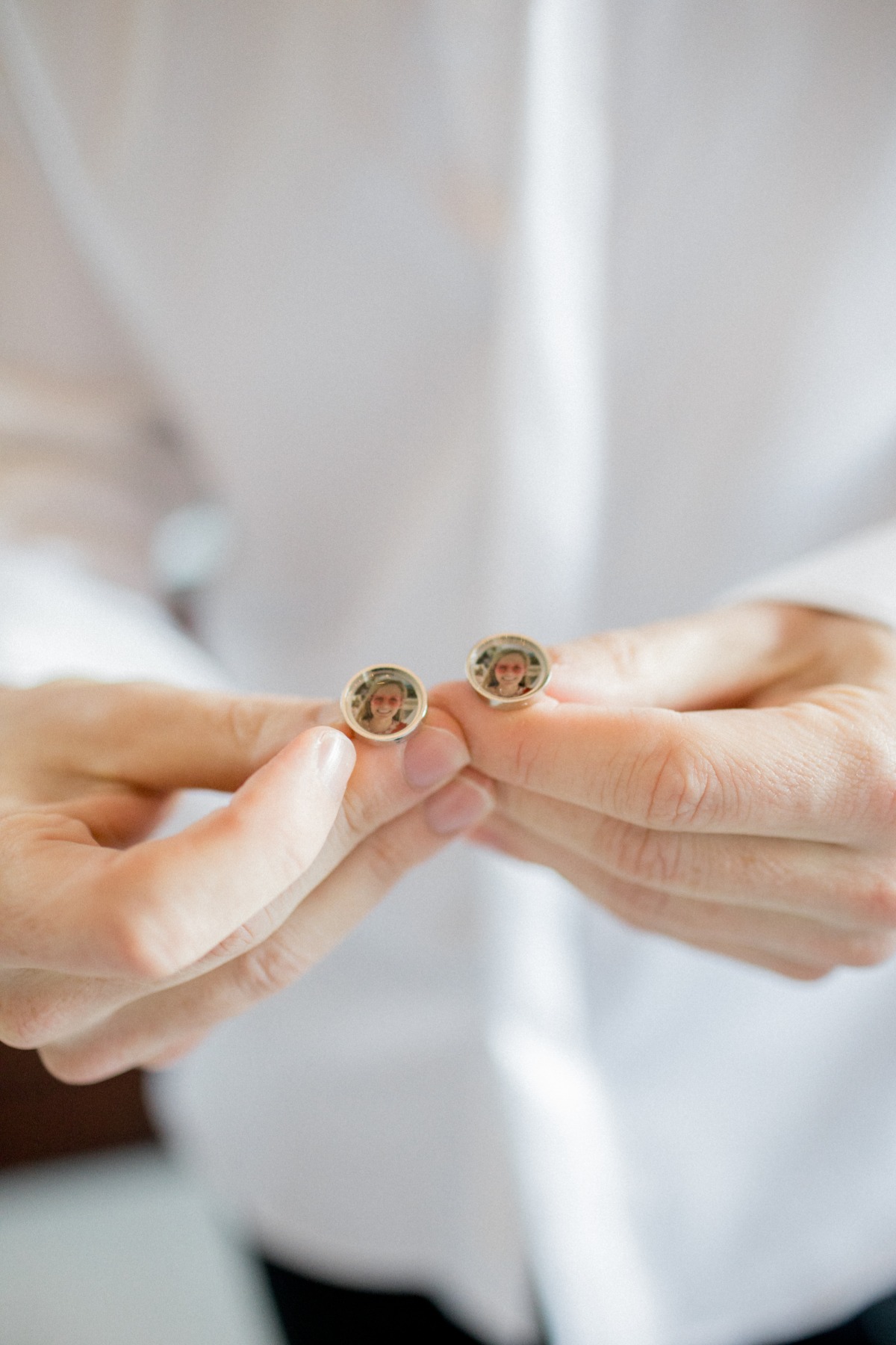 Hands holding cufflinks with photo of woman close up