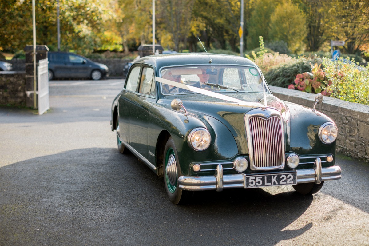 Classic green wedding car arriving, decorated with ribbons
