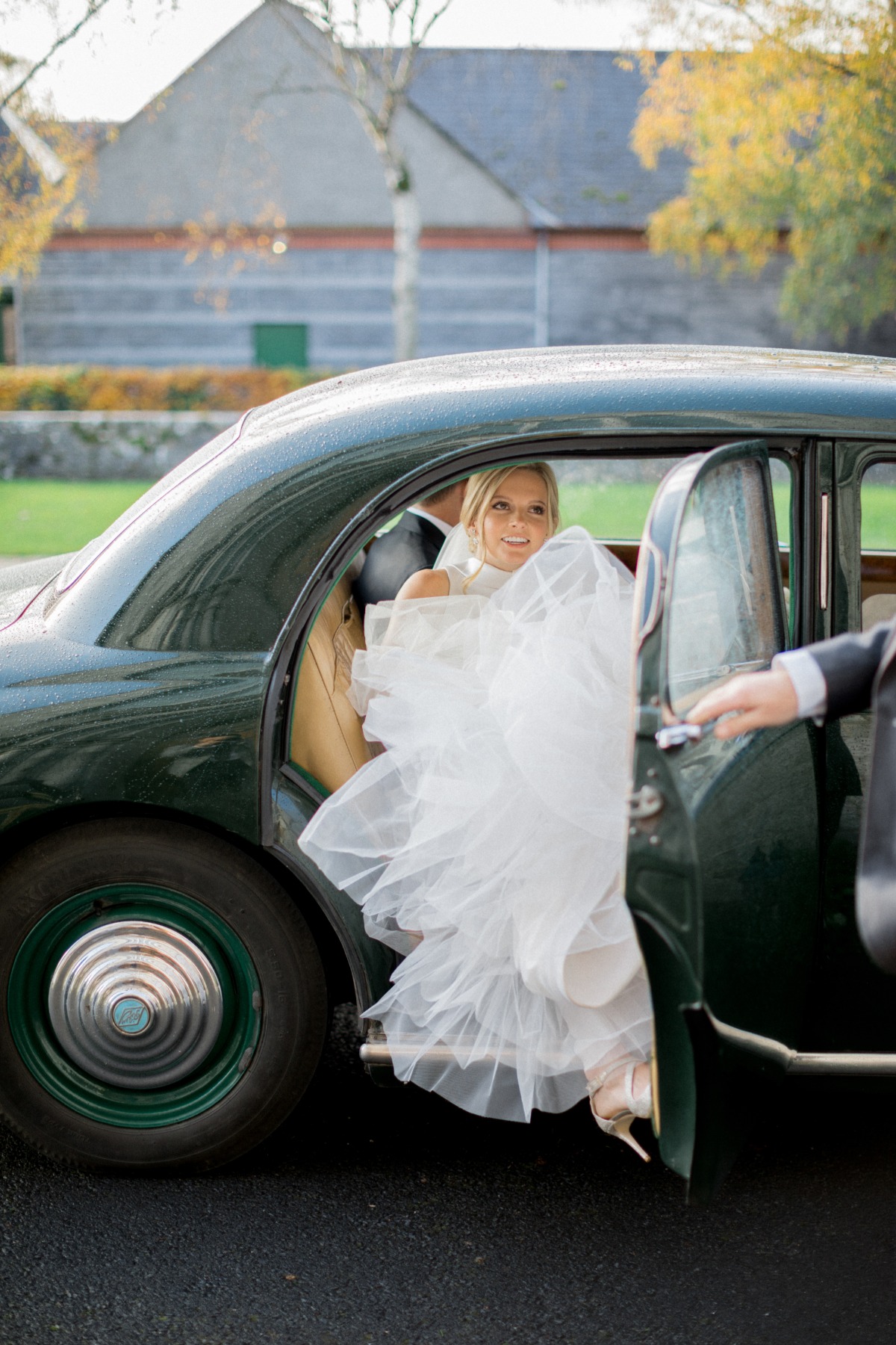 Happy bride exiting classic car on her wedding day