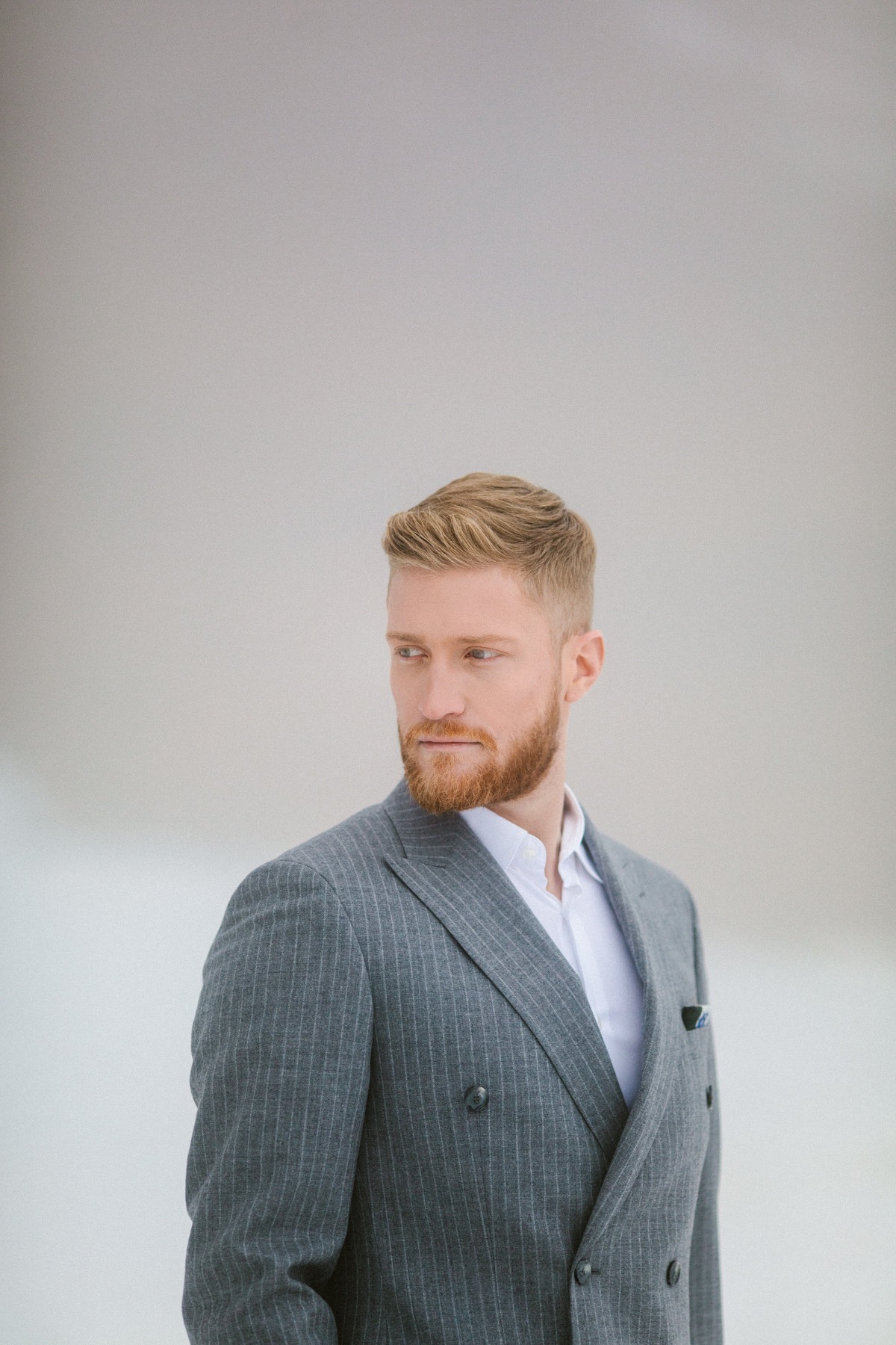 Stylish man with a beard in a grey striped suit looking away