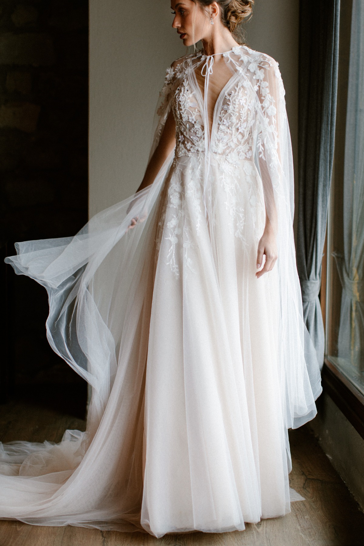 Elegant bride in a flowing wedding dress with a cape