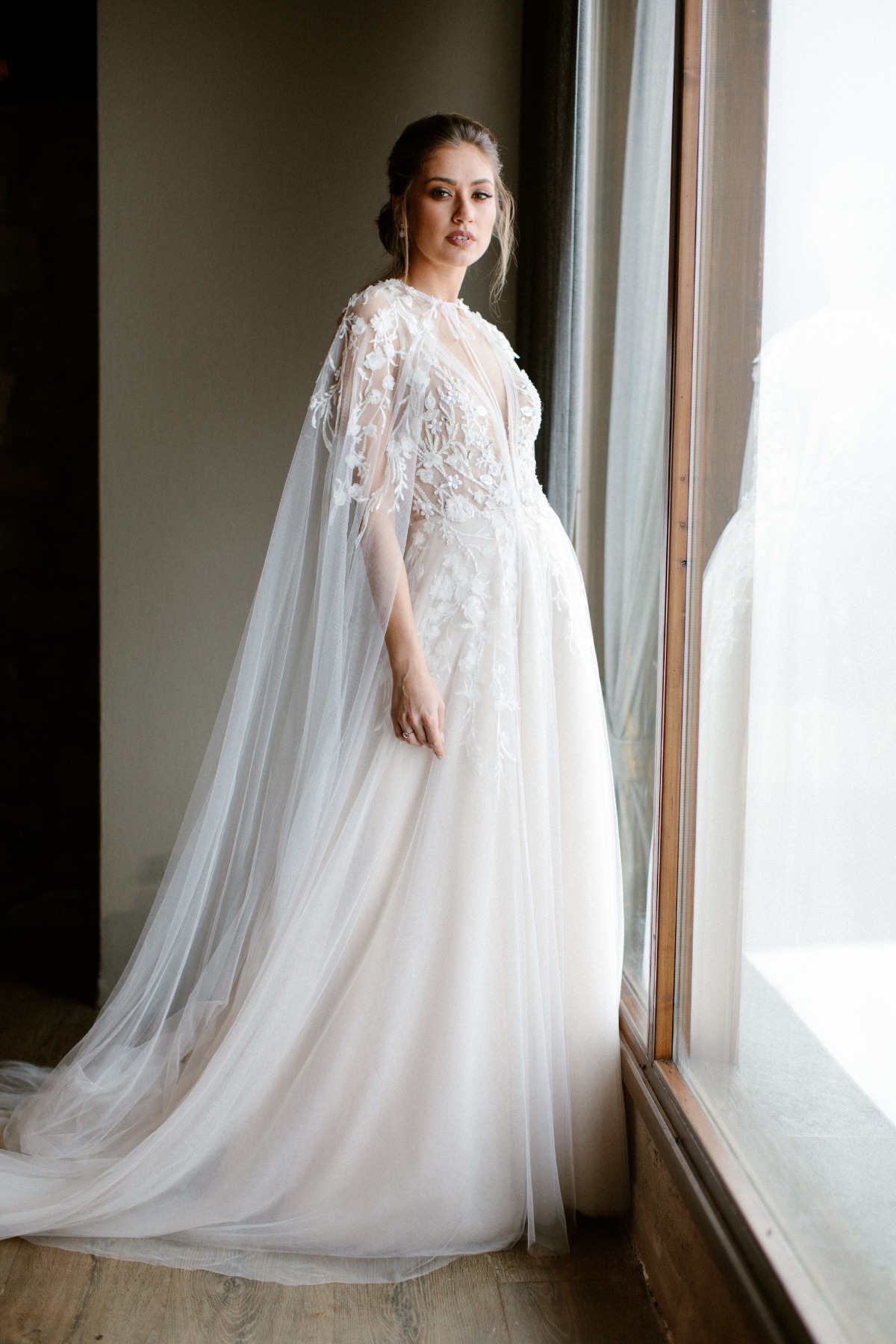 Elegant bride in a detailed wedding dress with a sheer cape