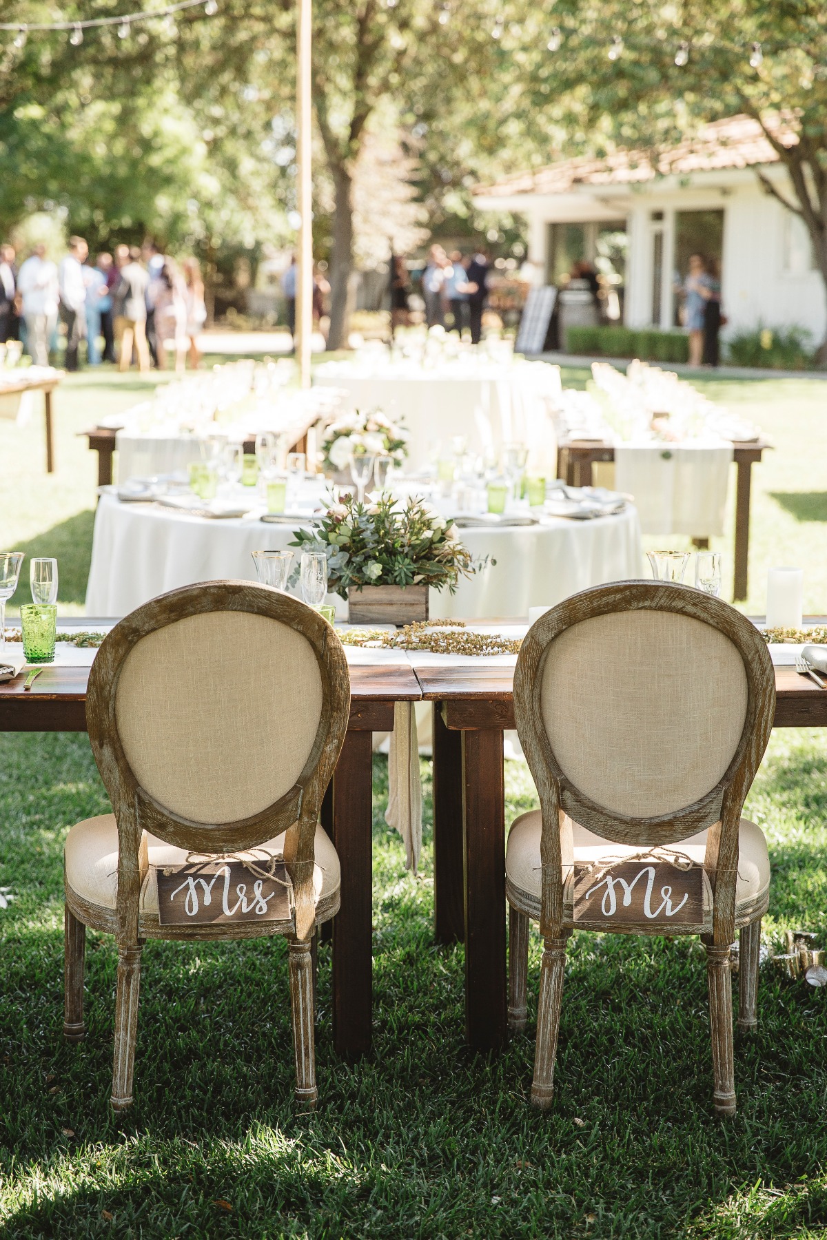 Mrs. and Mr. wooden signs hanging on chairs at sweetheart table
