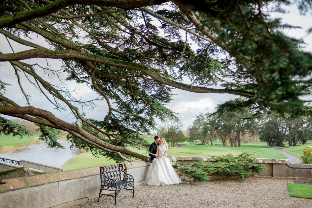 Bride and groom embrace under a tree at a park wedding