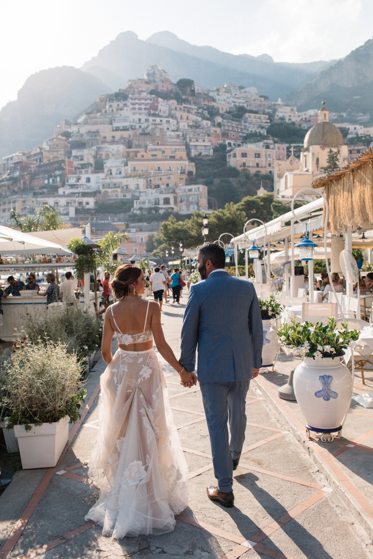 Bride and groom walk hand in hand in Positano Italy