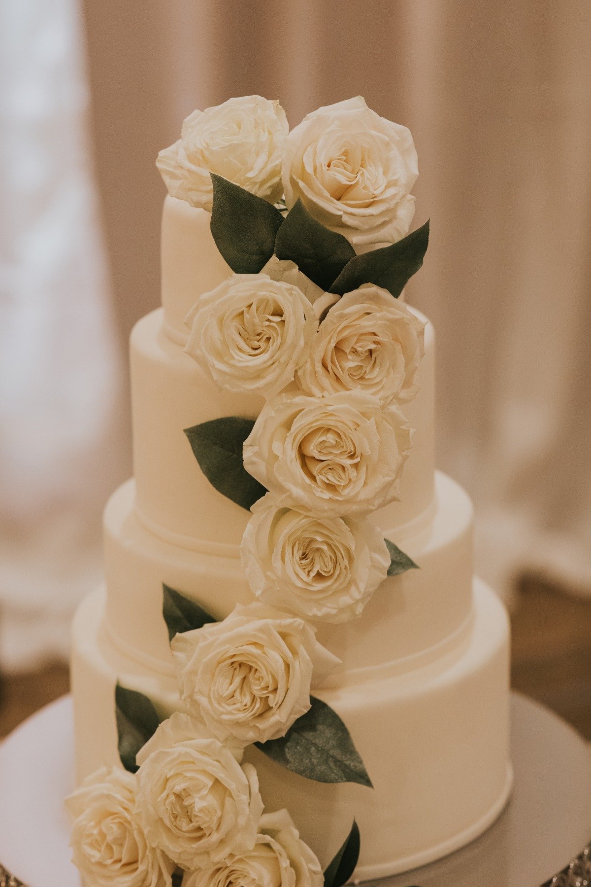 white wedding cake adorned with fresh white roses