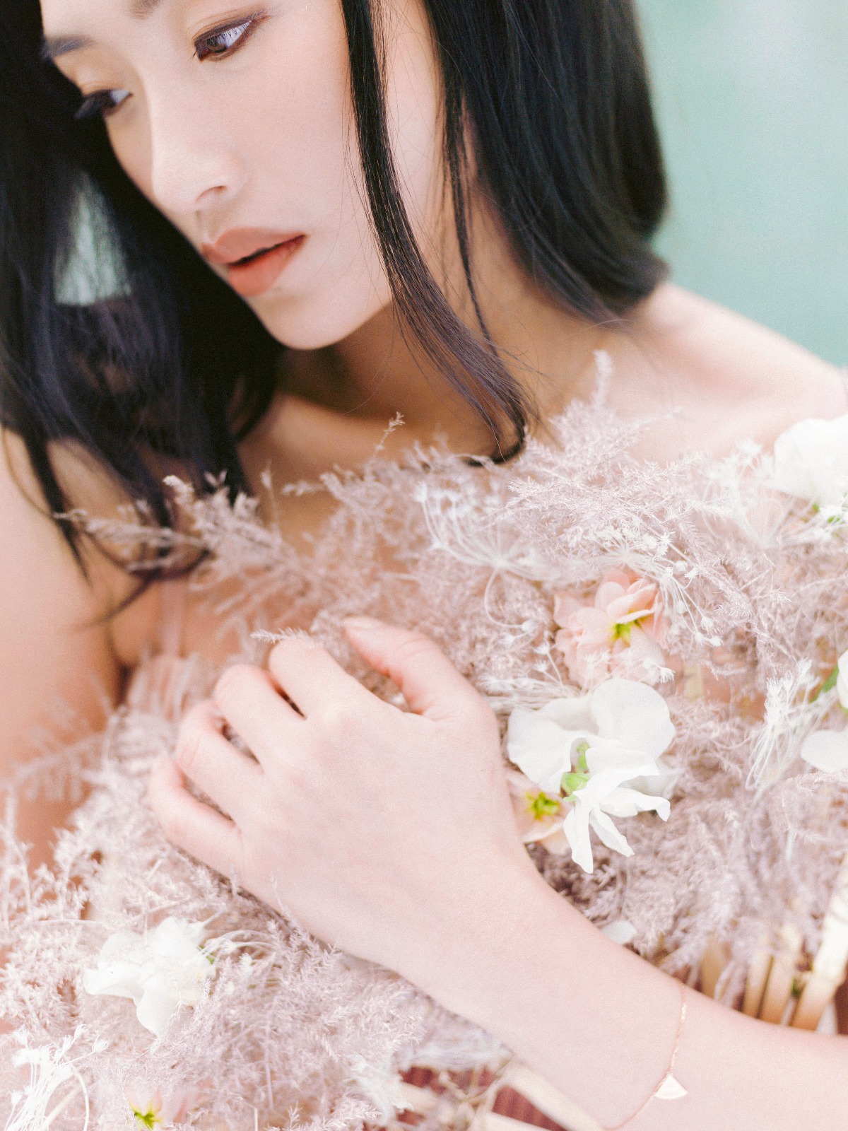 Elegant woman with long dark hair and floral details, gazing down