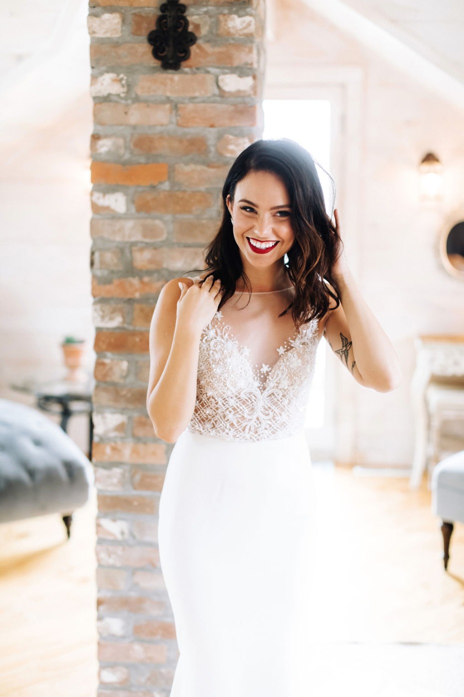 Beautiful bride smiling and adjusting her hair in a stunning wedding dress