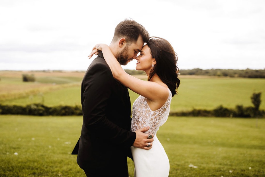 Romantic wedding couple embracing on a green field, love and happiness
