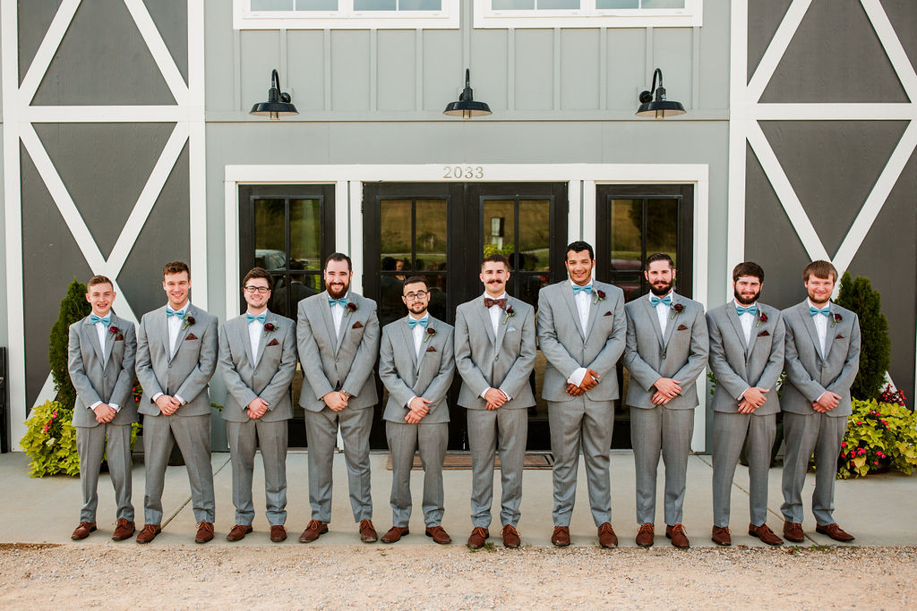 Groomsmen in grey suits and bow ties at a wedding venue