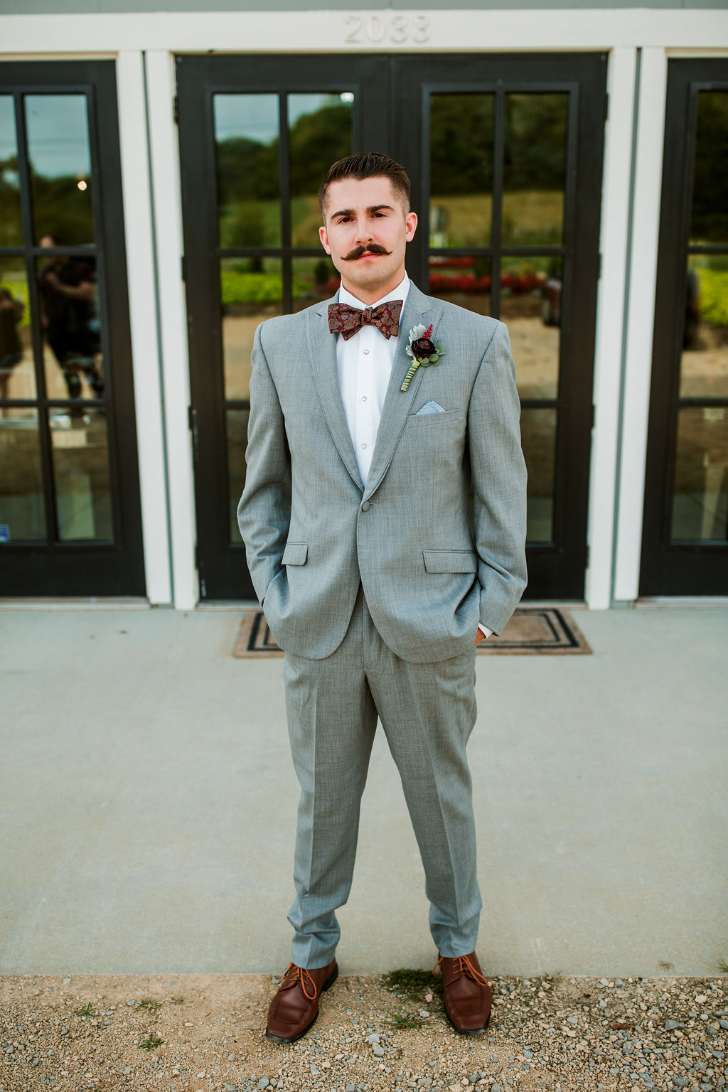 Groom in grey suit and bow tie with stylish mustache