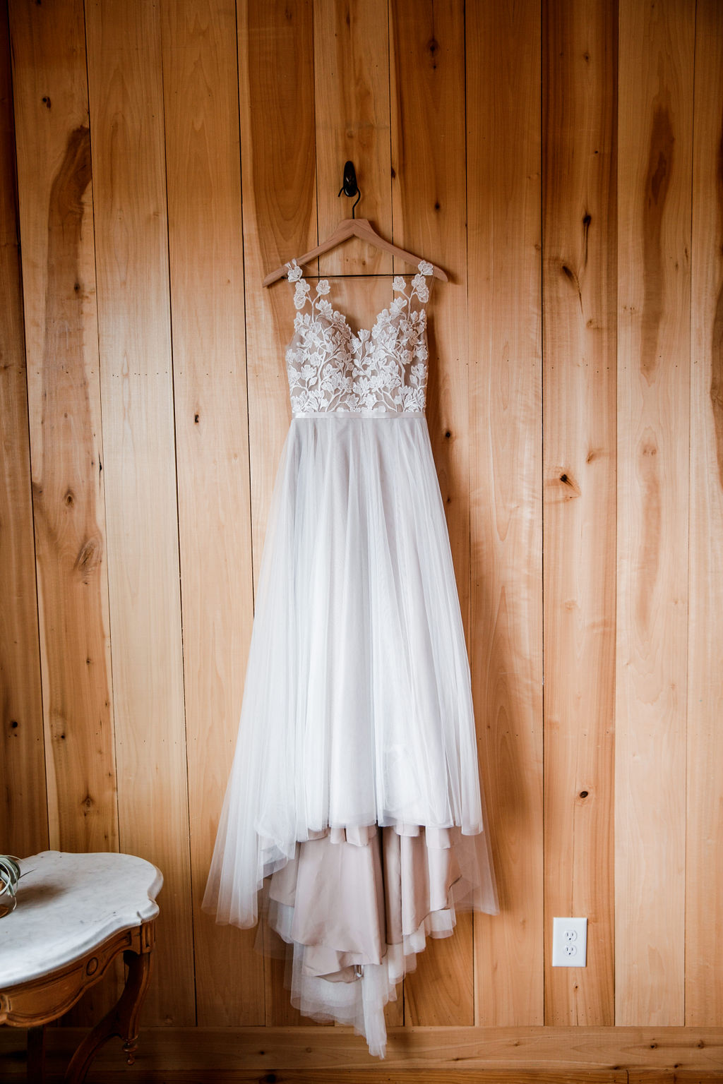 Elegant wedding dress hangs on a rustic wooden wall