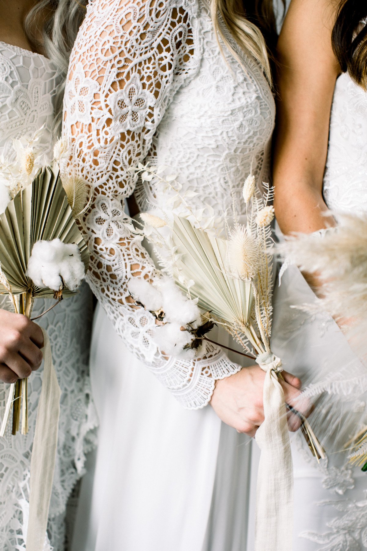 bridesmaids in white dresses holding pampas grass wedding bouquets