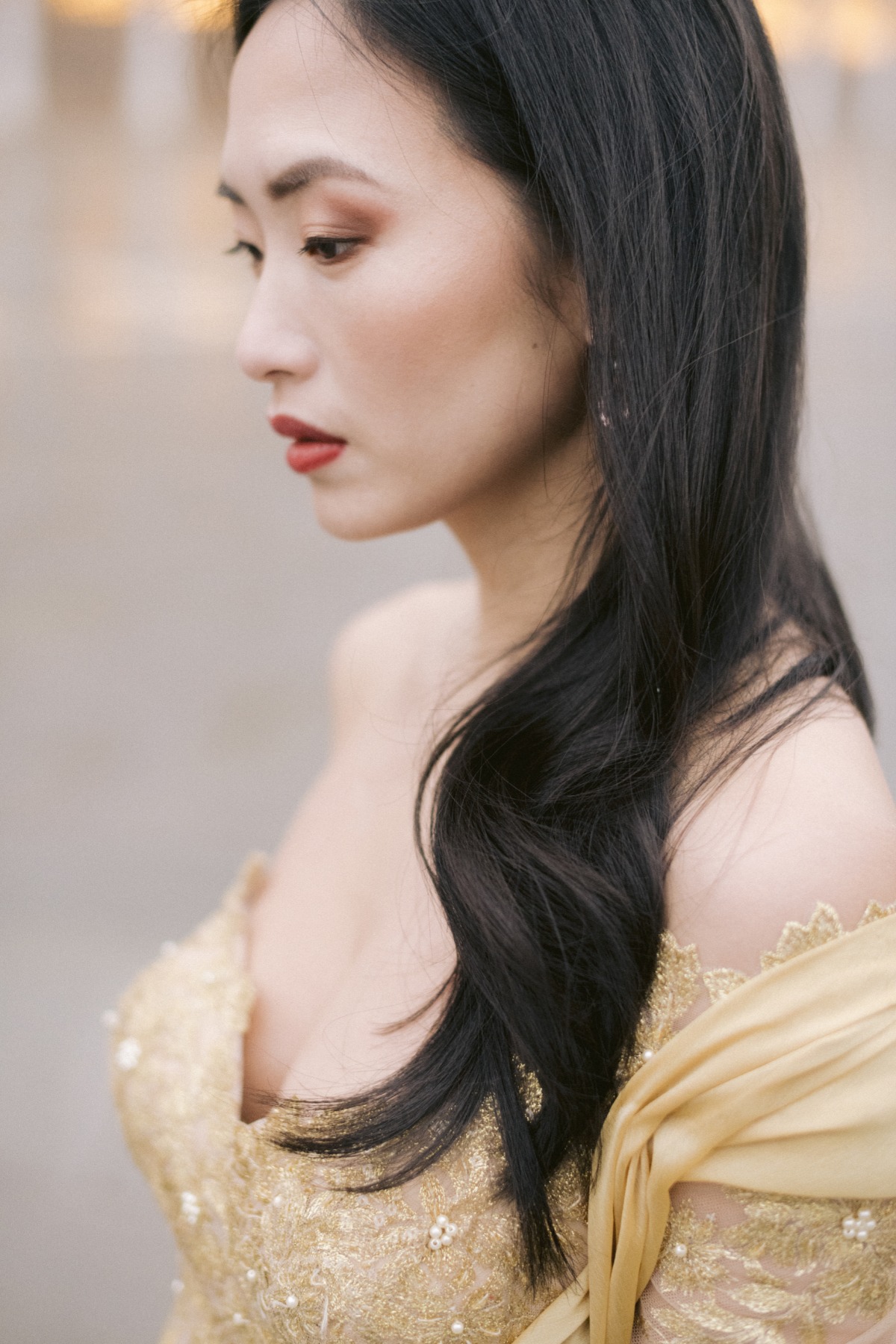 Elegant Asian woman in golden gown, looking thoughtful