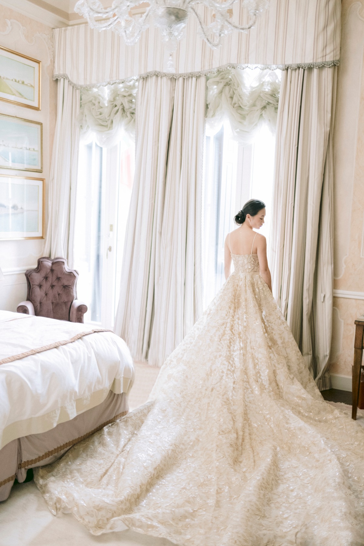 Bride in elegant gown by window, waiting to get married